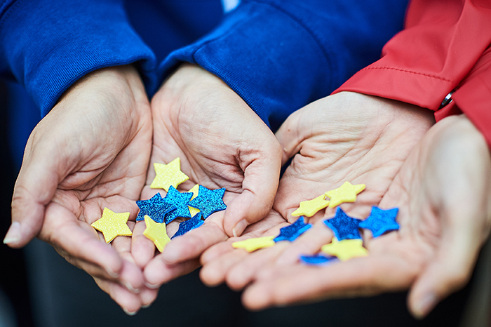 Hands holding stars in blue and yellow, the same colours of the EU flag